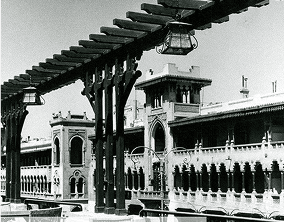A black and white image of a building with a lamp post in the foreground, set against a clear sky.