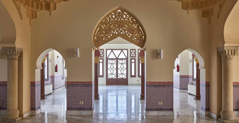 Decorative arched doorway with geometric glass pattern, ornate columns, and detailed tilework in an indoor setting.